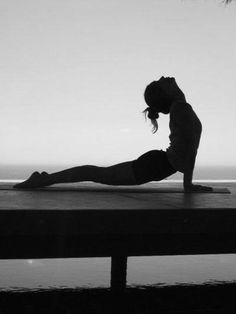 a woman is doing yoga on a dock