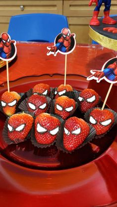 some strawberries are on a plate with spiderman stickers in the middle and other decorations around them