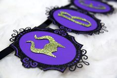 three purple and green hair clips with gold glitters on them sitting on a white fur surface