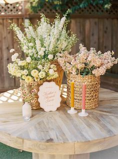 two baskets with flowers and candles on a table