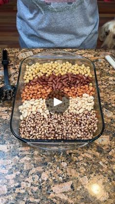 a glass dish filled with nuts on top of a counter next to a brown dog