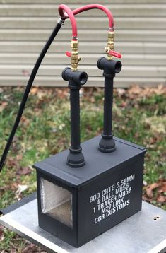 two red and black valves connected to each other on top of a metal box in the grass