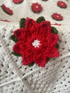 a crocheted blanket with a red flower on it