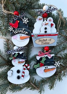 three snowman ornaments hanging from a christmas tree