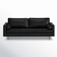 a black leather couch sitting on top of a white wall