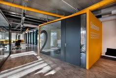 an office with glass walls and yellow accents