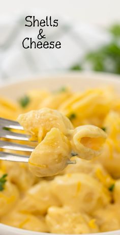 a fork full of shells and cheese with parsley on the side, in a white bowl