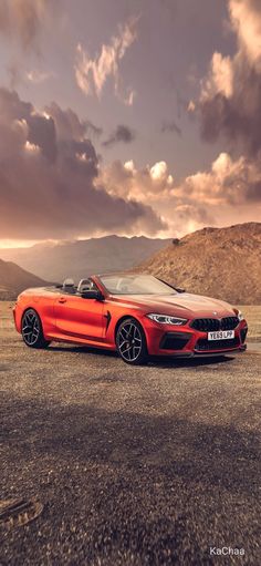 an orange bmw z4 roadster convertible parked in the desert under a cloudy sky