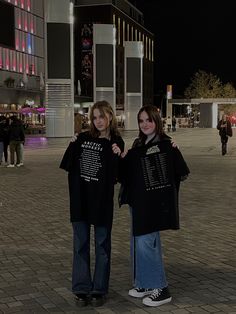 two young women standing next to each other in front of a building