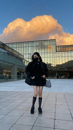 a woman is standing in front of a glass building with her hand on her hip