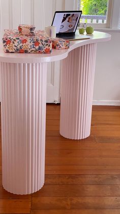 a table with a laptop sitting on top of it next to two pink pedestals