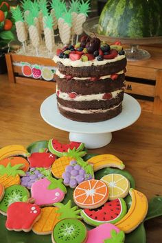 there is a cake with fruit on the top and cookies in the shape of fruits