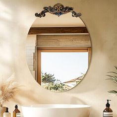 a bath tub sitting under a bathroom mirror next to a window with a potted plant