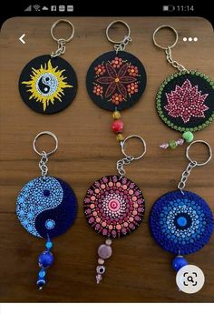 four key chains with different designs on them sitting on a wooden table next to each other