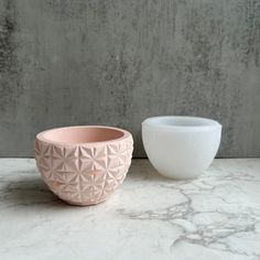 two white bowls sitting next to each other on a marble counter top with grey walls in the background