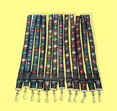 six lanyards with flowers on them are lined up against a bright yellow background