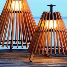 two wooden lamps sitting next to each other on a dock near the water at night