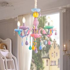 a pink chandelier hanging from the ceiling in a room with white furniture and windows