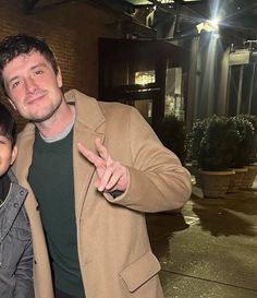 a man standing next to a little boy in front of a brick building at night