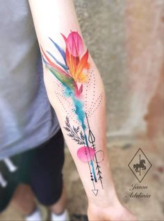 a colorful flower tattoo on the left forearm and arm with arrows around it, as well as an arrow