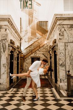 a man and woman are kissing in an old - fashioned hallway with marble walls, black and white checkered flooring