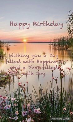 a birthday card with flowers in the foreground and a sunset on the water behind it