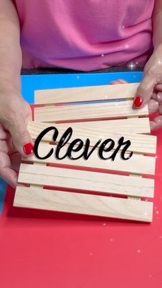 a woman is holding a piece of wood with the word clever written on it