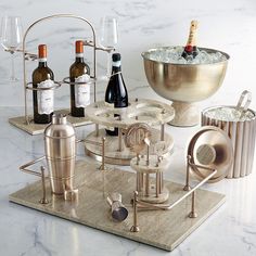 a marble table topped with bottles of wine and ice bucket next to a metal mixing bowl