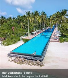 an aerial view of a long pool surrounded by palm trees and white sand on the beach