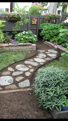 a garden with various plants and flowers in the back yard, along with a stone path