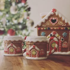 two gingerbread house mugs on a table with a christmas tree in the background