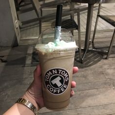 a person holding up a coffee drink with whipped cream on top and a straw in the cup