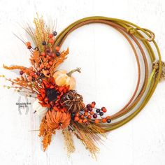 an arrangement of dried flowers and pumpkins is arranged on a white surface with rope