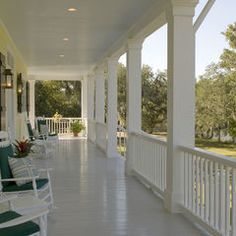 the porch is lined with white rocking chairs