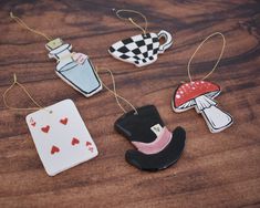 four ceramic ornaments are hanging on a wooden table with hearts and an empty card in the middle