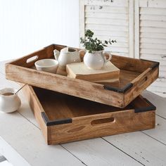 two wooden trays on top of each other with tea cups and books in them