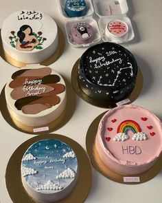 six decorated cakes on plates with writing and pictures in them, all sitting on a table