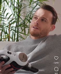 a man sitting on a couch holding a hair dryer