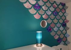 a blue vase sitting on top of a white table next to a wall covered in fish scales