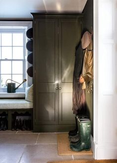 a mud room with green cupboards and rubber boots