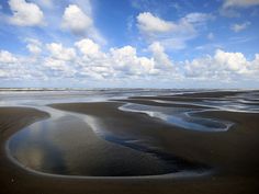 some water and sand under a cloudy blue sky