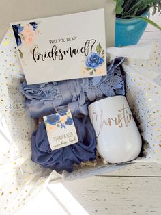 a bouquet of flowers in a gift box with a card and mug next to it