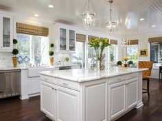 a large white kitchen with an island in the center and lots of windows on both sides