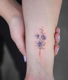 a woman's foot with purple flowers tattooed on the left side of her leg