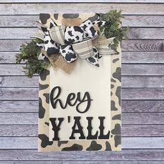 a wooden sign that says hey y'all on it with bows and camo print