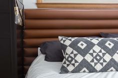 a close up of a pillow on a bed with a brown headboard and pillows