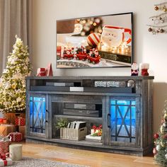 a christmas tree is in front of a flat screen tv on a stand with presents