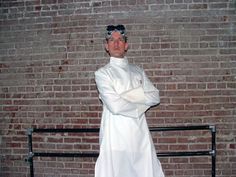 a man dressed as a chef standing in front of a brick wall with his arms crossed