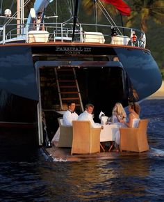 a group of people sitting at a table on top of a boat in the water