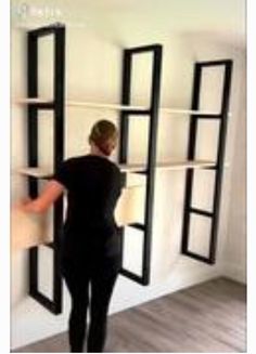 a woman is standing in front of some bookshelves and she has her hands on the shelves